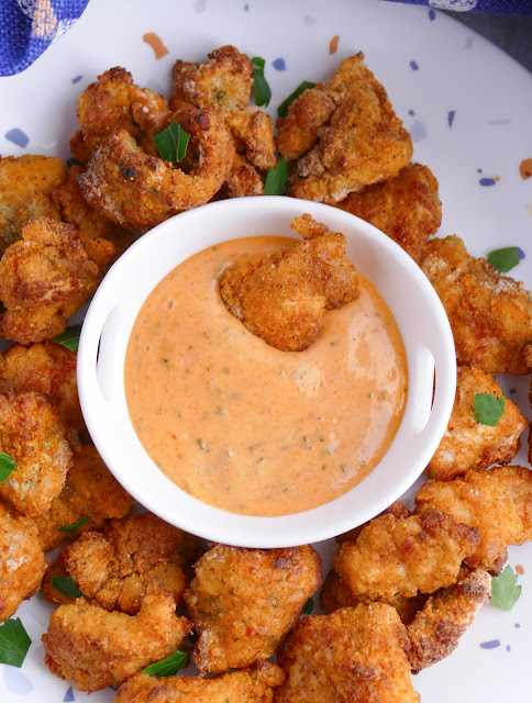 Air Fryer Catfish Nugget in a bowl of dipping sauce on a plate with more nuggets.