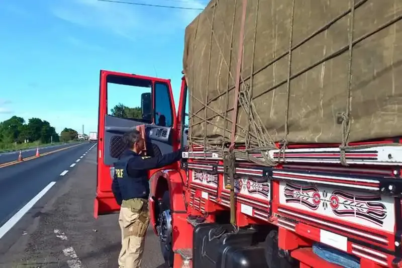 Agente da PRF durante abordagem de um caminhão vermelho