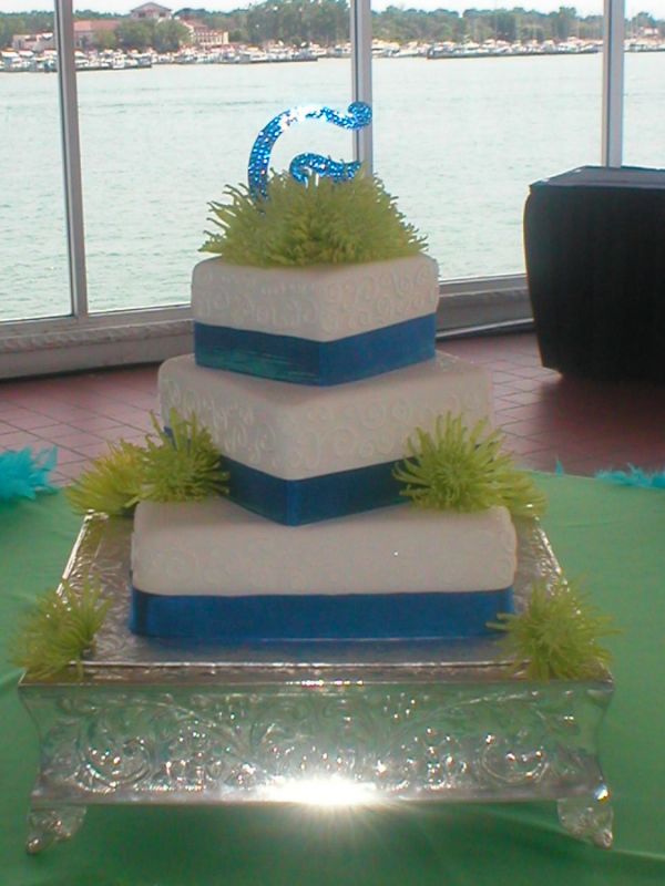 A small round wedding cake with blue lines and green flowers including 