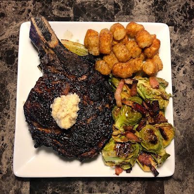 Rare grilled bone-in Angus ribeye along with some tater tots and maple bacon roasted giant Brussels sprouts