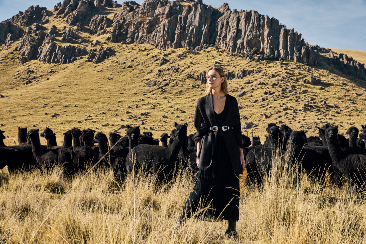 Mujer en medio de campo de alpacas negras con colección Black Alpaca de Kuna