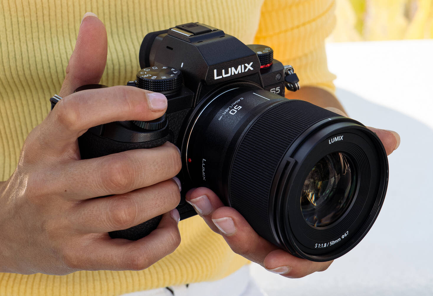 Камера Panasonic Lumix S5 с объективом Lumix S 50mm f/1.8 в руках фотографа