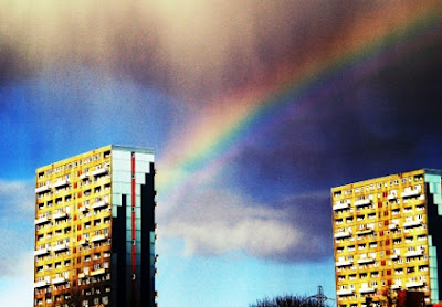 Two blocks of high flats in Glasgow with a cloudy sky and rainbow