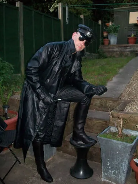 Leatherman showing off boots wearing a black leather trench coat