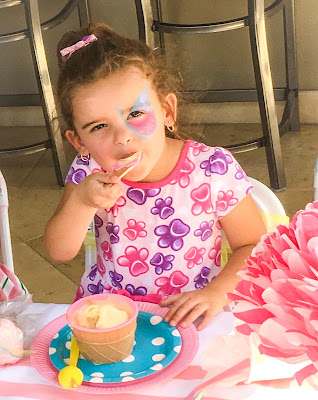 Little girl in a pink dress eating ice cream