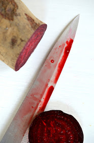 Eine Messerklinge ist rot getränkt vom Durchschneiden der Roten Rübe.