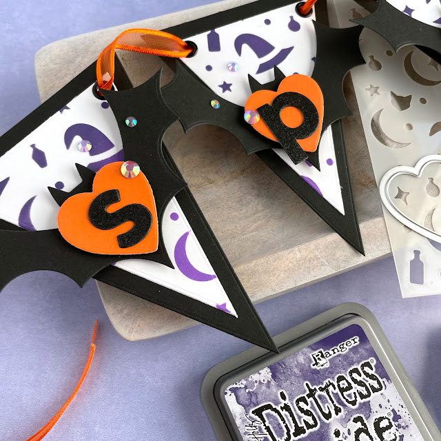 Spooky Halloween Banner created with: Scrapbook.com halloween bats die, magic potion stencil, glitter paper metals, smooth cardstock rainbow, domed foam blending tool, nested hearts, bold basic alpha, nested triangle banner; Tim Holtz distress oxide villainous potion, wilted violet; Pinkfresh jewels