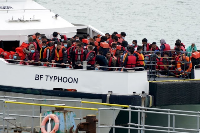 Migranti su una barca scortati dalla polizia britannica a terra (archivion)