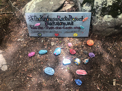 Painted sign saying, "#TheKindnessRockProject Blackstone, MA Take one - Share one- Leave one 1 message can change someone's day"