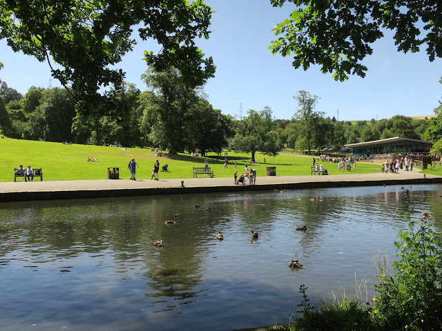 Lake, trees, grass, cafe and people at Shibden Park, Halifax, West Yorkshire.