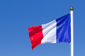 Pic of French flag flying at top of flagpole against clear blue sky