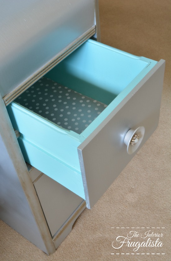 How to give a vintage waterfall vanity a drab to fab hollywood glam makeover with metallic paint, wrapping paper, and pearl embellished knobs.