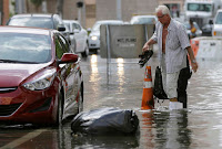 In this Sept. 30, 2015 file photo, a hotel guest carries his shoes as he is escorted to his car along in Miami Beach, Fla. The street flooding was in part caused by high tides due to the lunar cycle, according to the National Weather Service. A new scientific report finds man-made climate change played some kind of role in two dozen extreme weather events around the world in 2015. But it also detected no global warming fingerprints in a handful of other weird weather instances. (Credit: AP Photo/Lynne Sladky, File) Click to Enlarge.