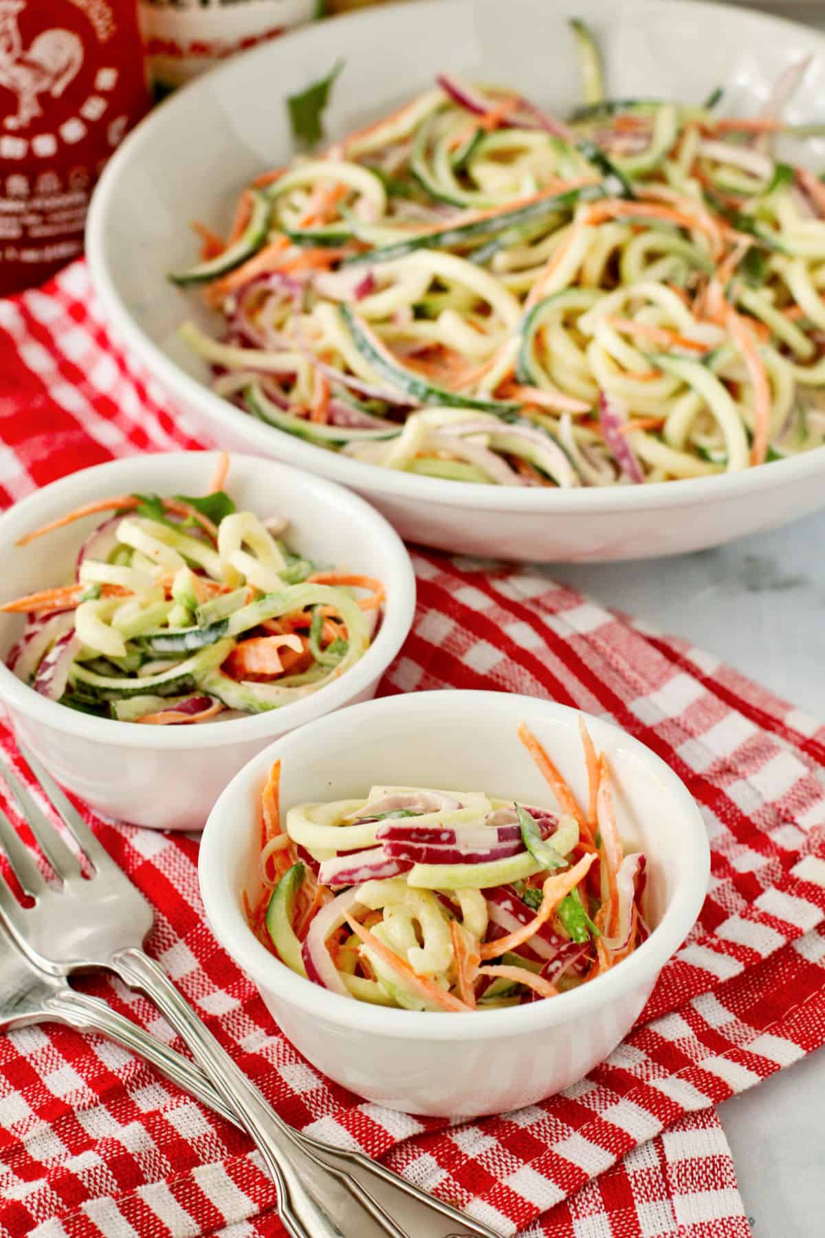 Zucchini Slaw in two small bowls with the larger bowl in the back.