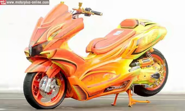 Foto Modifikasi Honda PCX Airbrush berkonsep batik ala bikers gradasai warna orange dan hijau dipilih menampilkan kesan mencolok ban merk Corsa disanding pelek Piaggio X9 shockbreaker depan dipasangi merk NTC dibagian lampu satu mengaplikasi reflektor, disatu sisi lainnya pakai LED Projector