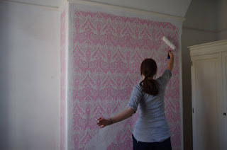 DIY Girl painting over pink wallpaper