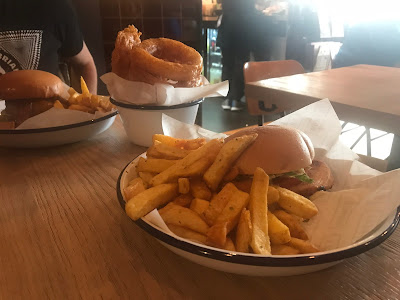 two burgers and a bowl of onion rings on a table