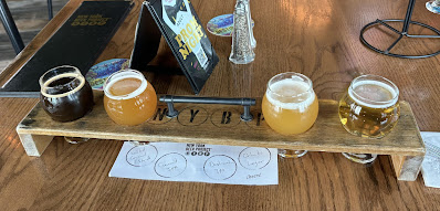 a flight of four different colored beers in a wooden frame.