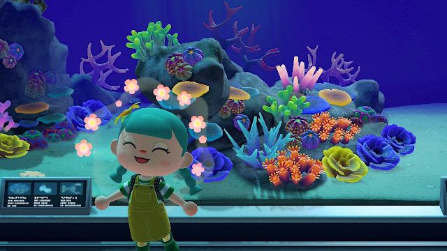 A screenshot from Animal Crossing New Horizons showing a happy character in front of a coral reef aquarium at the museum