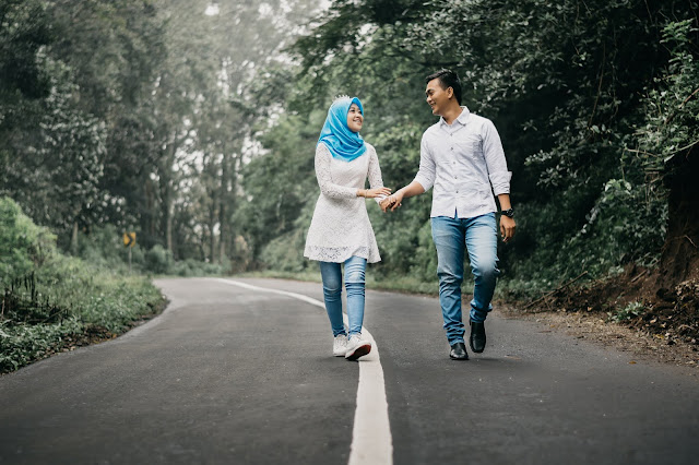 Man and woman walking on road holding hands