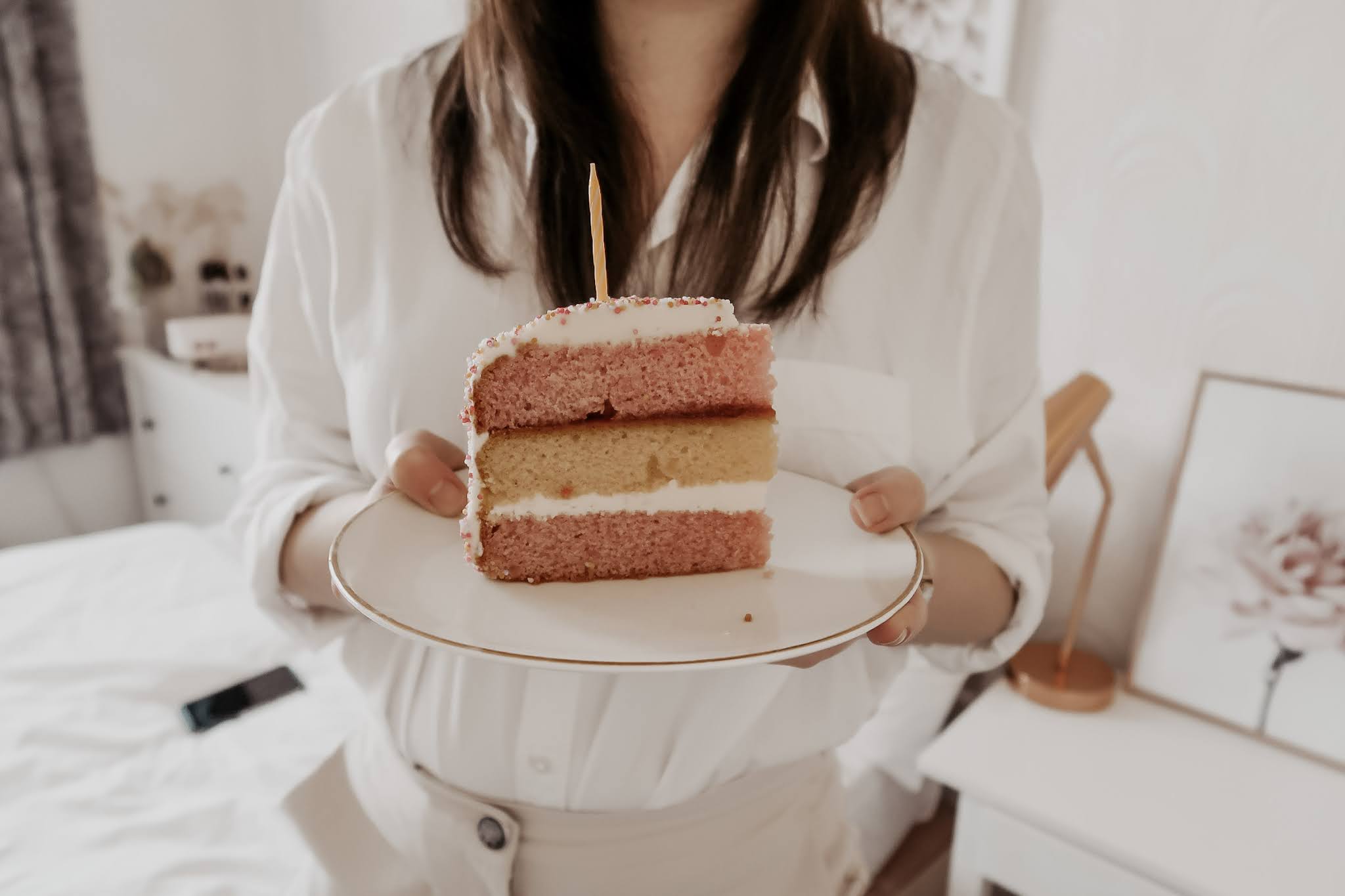 A woman holding a slice of pink cake on a plate.