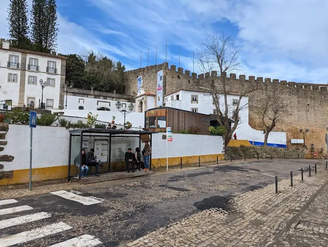 Bus stop in the foreground with views of Obidos town walls in the distance