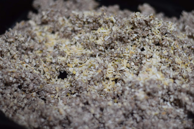 Dried minced onion being added to the walnut meat in the pan