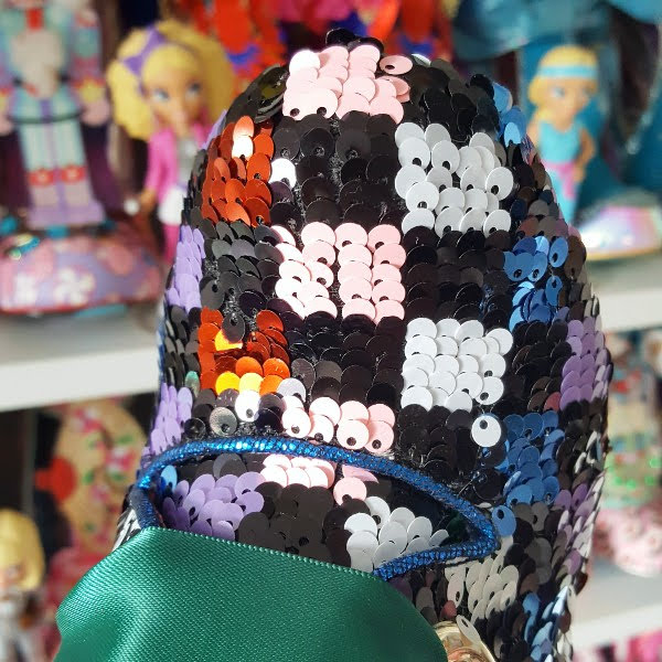 close up of round sequins toe on boot with shoe shelves in background