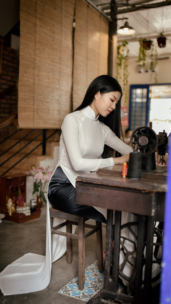 Thiếu nữ áo dài trắng ngồi máy may