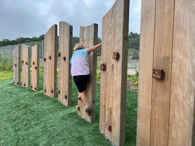 a girl working her way along a wooden climbing wall