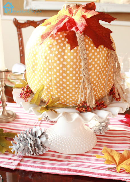 yellow polka dot pumpkin on white cake platter - pinecones and striped runner 