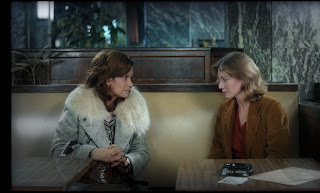 An image from the film The Meetings of Anna. Two women are sat in a booth in a café.