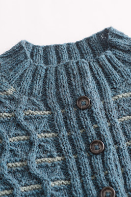 Detail of hand knit cardigan showing cable pattern and button band