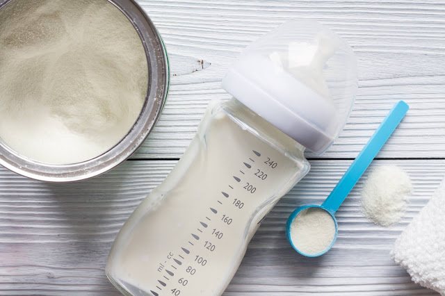 Tin of breast milk, scoop and baby bottle