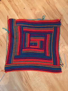 The finished tote side: all of the sections were worked in stripes red, orange, green, and blue. A center square is surrounded by 3 rounds of rectangles that get longer as they move out from the center. Each section is 12 garter stitch ridges high and varies in length according to the length of the pieces below it.