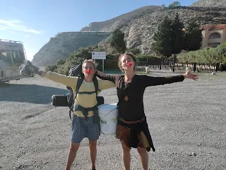 Murielle and Danielle on a road with open arms and red hibiscus flowers in the mouths