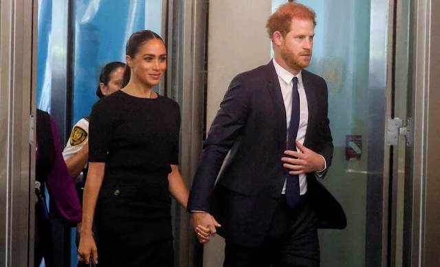 Meghan Markle wore a black knit gold button pencil skirt by Givenchy. Mulberry leather bag. Manolo Blahnik suede pumps