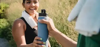 At the gym, a cheerful woman holds a water bottle. physical health