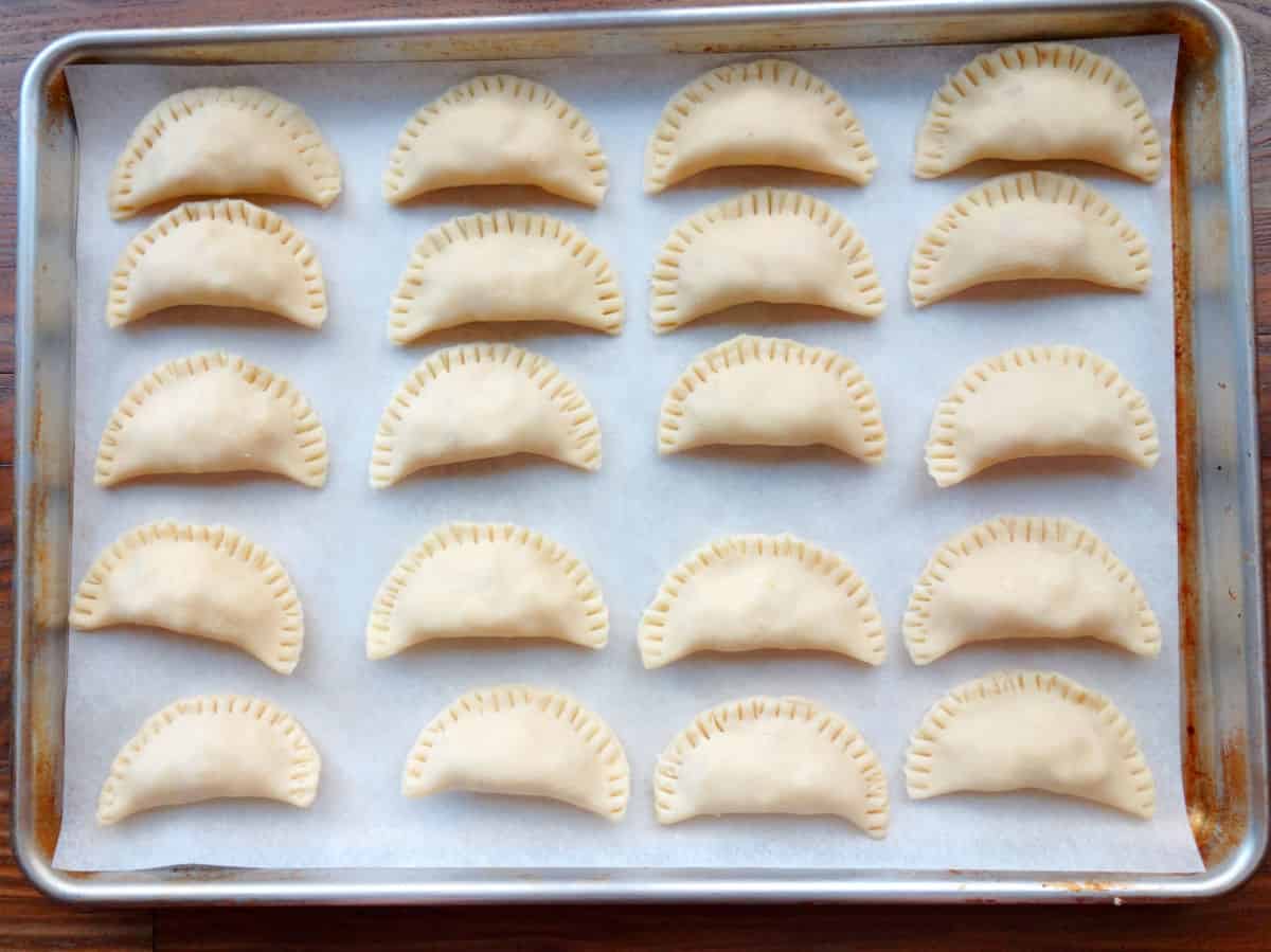 Empanadas on a sheet pan before baking.