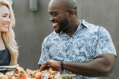 Interracial couple smiling at each other over barbecue