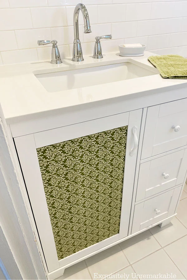 White Bathroom Vanity with decorative green paper on center door panel