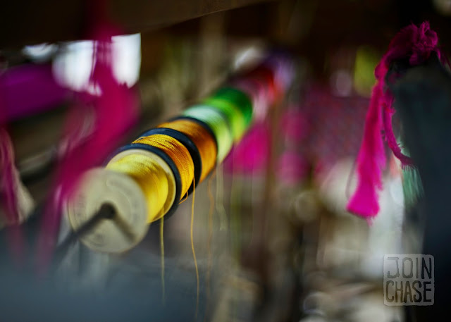 Colorful thread hanging above a wooden loom in Sagaing Division, Myanmar.