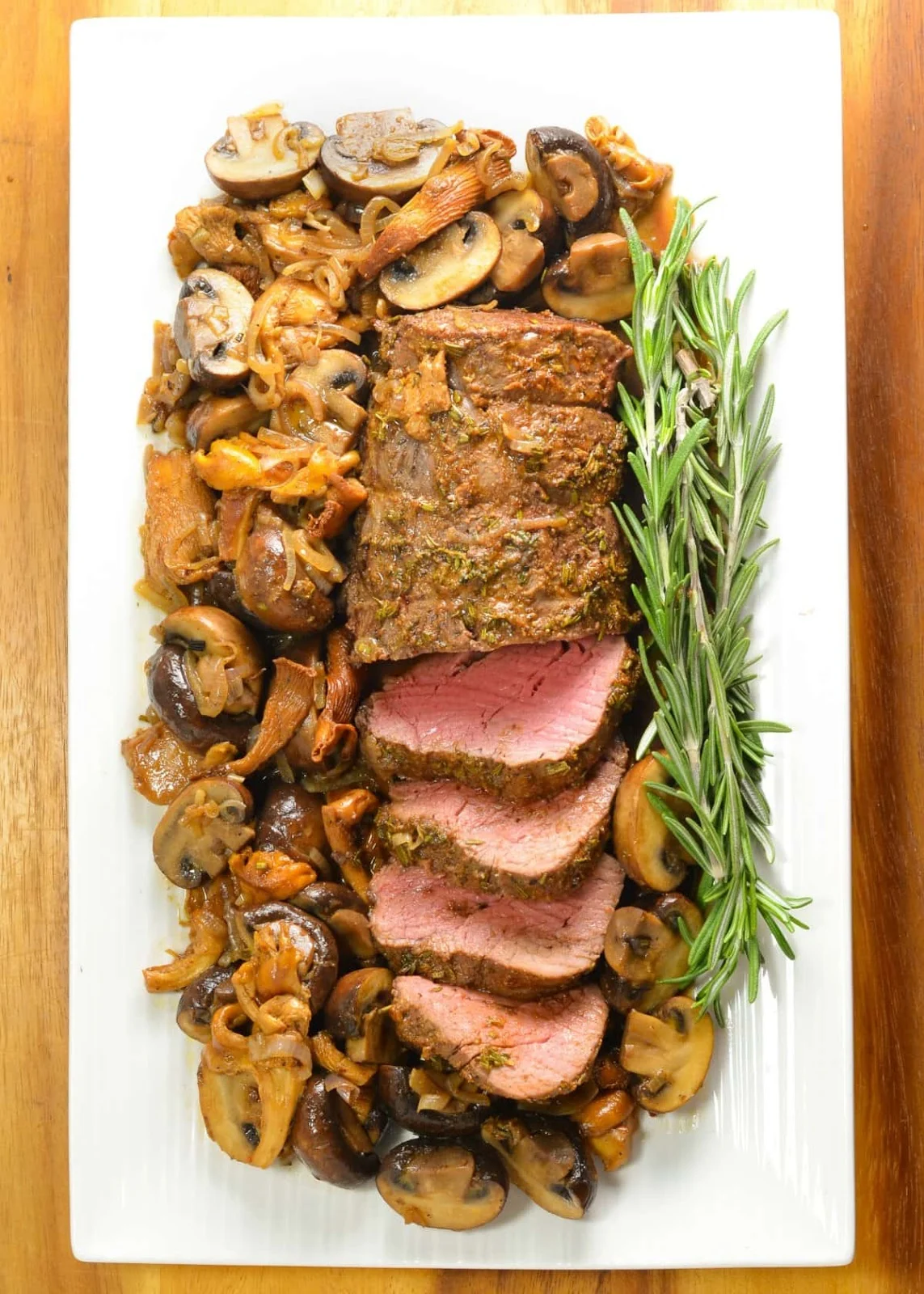 A down shot of Beef Tenderloin Roast with Mushrooms on a white tray.