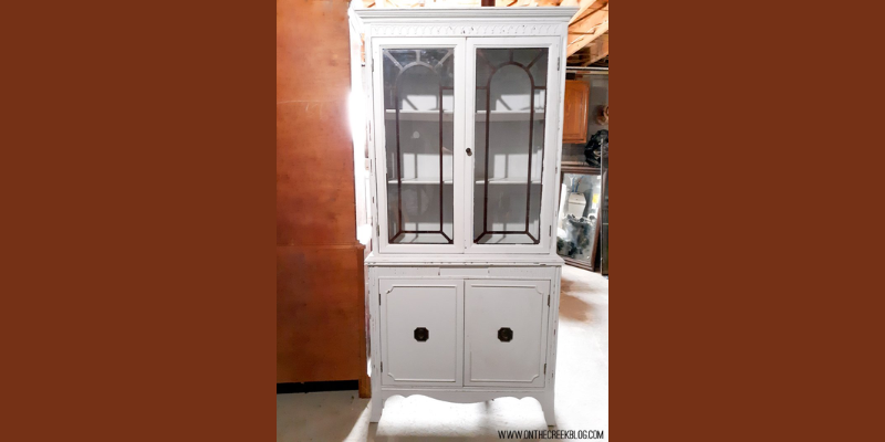 A creatively transformed hutch from Habitat For Humanity ReStore, repainted by Tiff in chippy white with red accents, showcasing a distressed finish and a blend of old and new charm. | on the creek blog // www.onthecreekblog.com