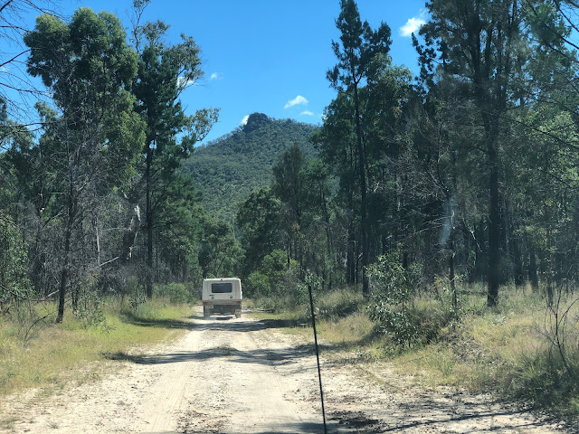 Rear view of Isuzu driving on sandy road towards a hill