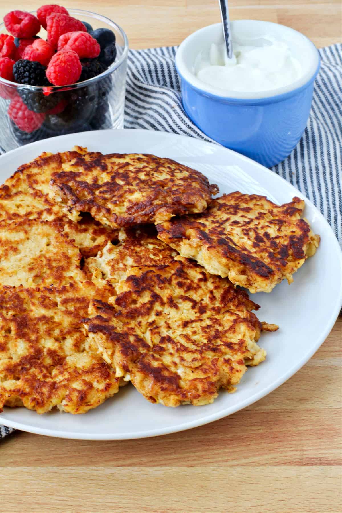 Apple Latkes on a plate with berries in the background.