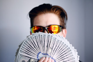 Shane with a fan of American one hundred dollar bills after getting paid. Photo by Shane on Unsplash - https://unsplash.com/photos/man-in-black-framed-sunglasses-holding-fan-of-white-and-gray-striped-cards-U_ekGjoIm_E