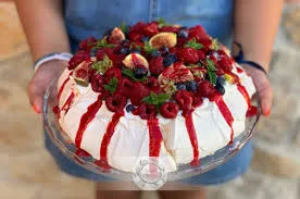 Uma Pavlova bem recheada na mão de uma pessoa