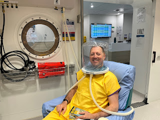 Joel wearing pyjamas and a special helmet in the hyperbaric chamber