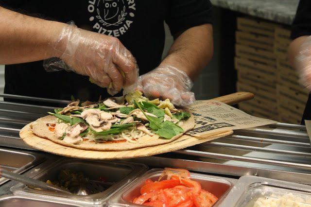 Pizza piled high with fresh ingredients at Olive Theory Pizzeria